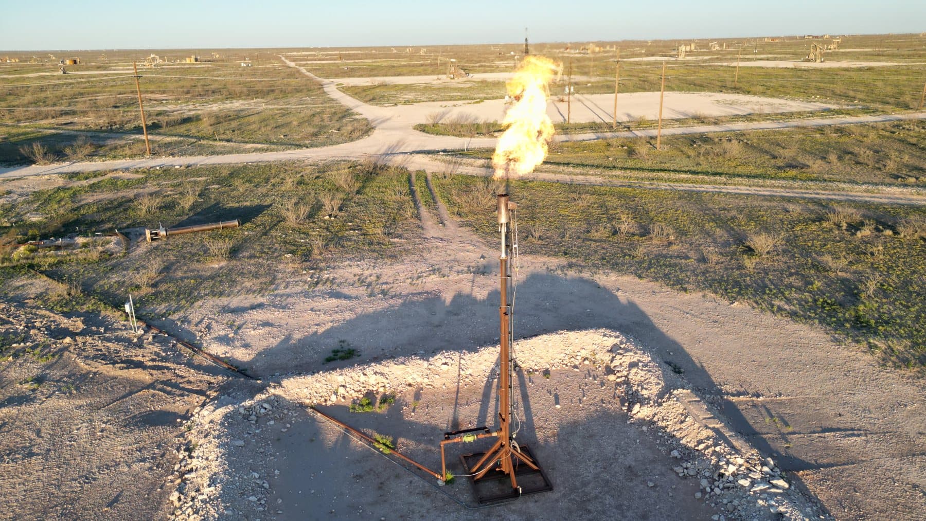 Smokeless flare burning clean with no visible smoke on a Permian Basin well pad, drone view